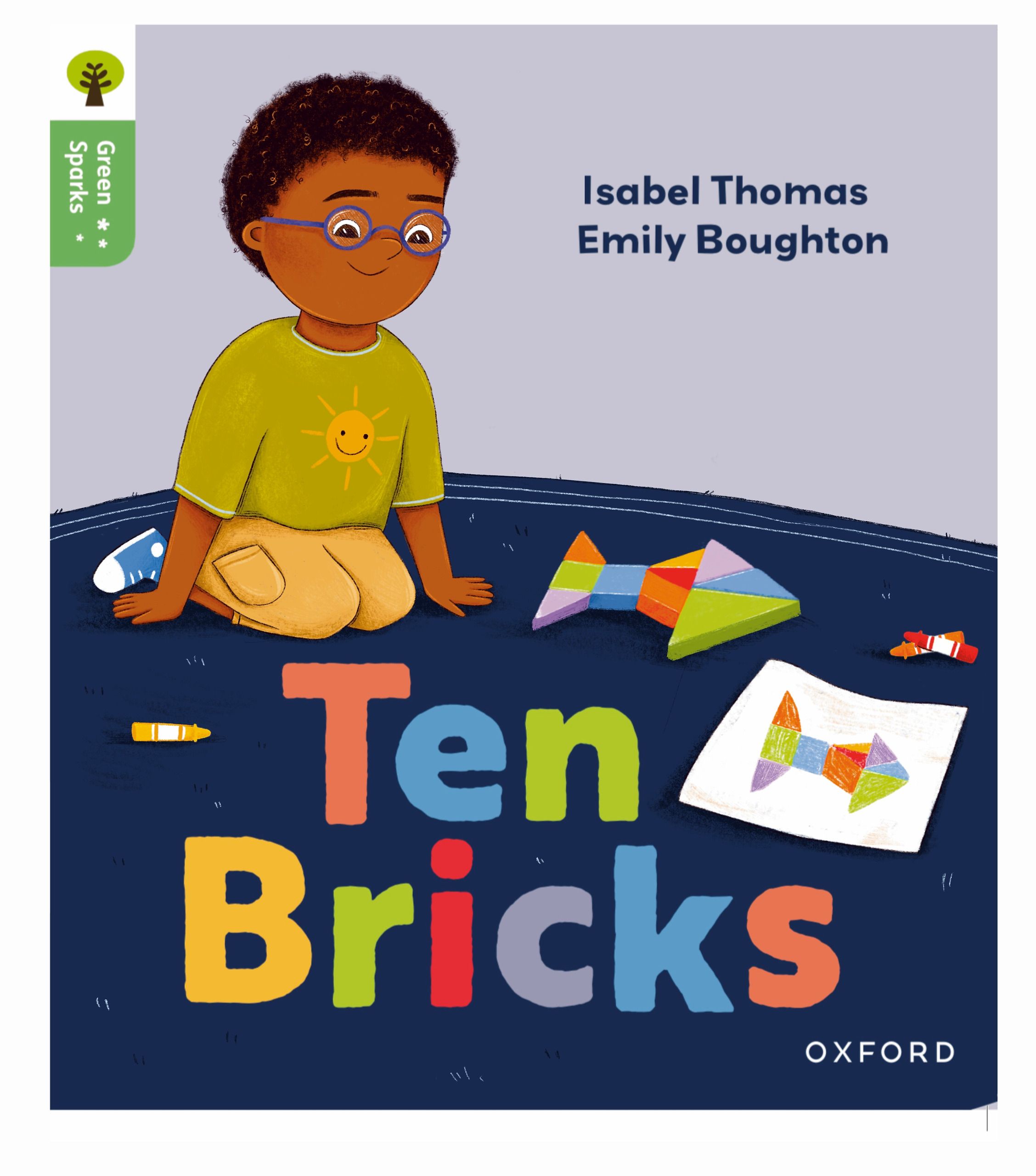 Book cover. A boy in round purple glasses and a green sun-print t-shirt kneels on a dark blue classroom rug, looking up from a rocket he has built out of coloured wooden blocks. His crayon drawing of the same rocket lies beside him, and the title is hand-lettered in blocks of colour across the rug.